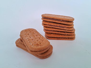 Narin bir dokuya sahip altın kahverengi bisküviler, bir fincan çayla veya lezzetli bir aperatifle eğlenmek için mükemmel, beyaz bir arka plan izole edilmiş.