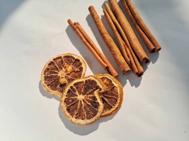 Kurutulmuş tarçın çubukları ve kurutulmuş limon dilimleri, beyaz arka planda izole edilmiş..