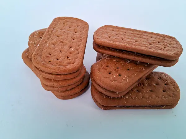 Narin bir dokuya sahip altın kahverengi bisküviler, bir fincan çayla veya lezzetli bir aperatifle eğlenmek için mükemmel, beyaz bir arka plan izole edilmiş.