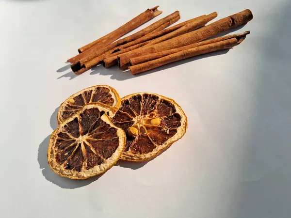 Kurutulmuş tarçın çubukları ve kurutulmuş limon dilimleri, beyaz arka planda izole edilmiş..