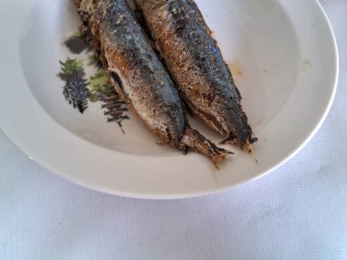 Beyaz bir kasede kızarmış uskumru balığı, beyaz bir arkaplan.