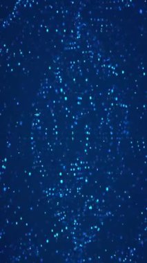 Koyu mavi arka planda mavi parlak parçacıklar. Şenlikli tasarımlar, arka planlar, kutlamalar, soyut kavramlar ve parti temaları için uygundur..