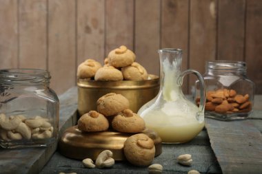 Soğutma rafında kaju fıstıklı kurabiyeler, yakın mesafede, ceviz ve elmas dolu cam kavanozlar, ve yanında da küçük bir kavanoz erimiş eritilmiş erik.. 