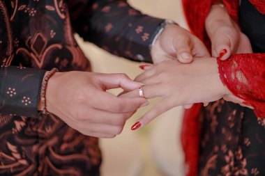 Nişan yüzüğü iğneleniyor. Nişan yüzüğünü gösteriyorum. El ele tutuşmak. Nişan fotoğrafı konsepti. Endonezyalı çift