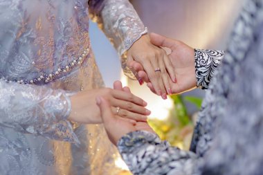 Nişan yüzüğü iğneleniyor. Nişan yüzüğünü gösteriyorum. El ele tutuşmak. Nişan fotoğrafı konsepti. Endonezyalı çift