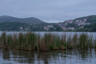 Arka planda dağlarda gölü olan güzel bir manzara. Baharda Yunan kenti Kastoria 'nın manzarası. Dağ gölünün kıyısındaki eski bir kasaba.