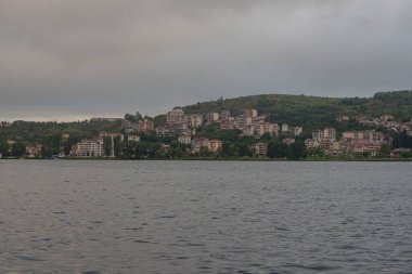Arka planda dağlarda gölü olan güzel bir manzara. Baharda Yunan kenti Kastoria 'nın manzarası. Dağ gölünün kıyısındaki eski bir kasaba.