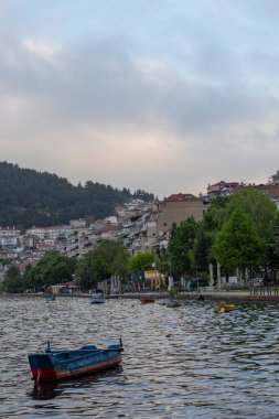 Arka planda dağlarda gölü olan güzel bir manzara. Baharda Yunan kenti Kastoria 'nın manzarası. Dağ gölünün kıyısındaki eski bir kasaba.