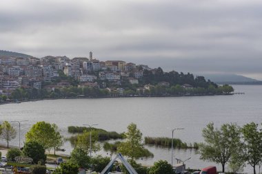 Arka planda dağlarda gölü olan güzel bir manzara. Baharda Yunan kenti Kastoria 'nın manzarası. Dağ gölünün kıyısındaki eski bir kasaba.