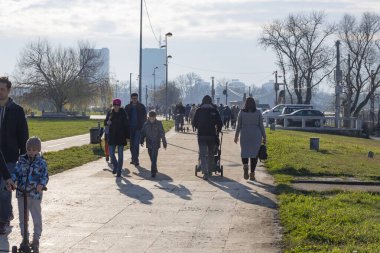 Sıcak bir kış gününde Belshrada parkında şehir seti. İnsanlar nehir boyunca parkta yürürler. Bnlgrad, Sırbistan 01.01.2022