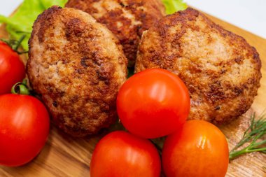 Ahşap arka planda sebzeli kızarmış tavuk pirzolası. Tahtada domatesli et topları ve otlar..