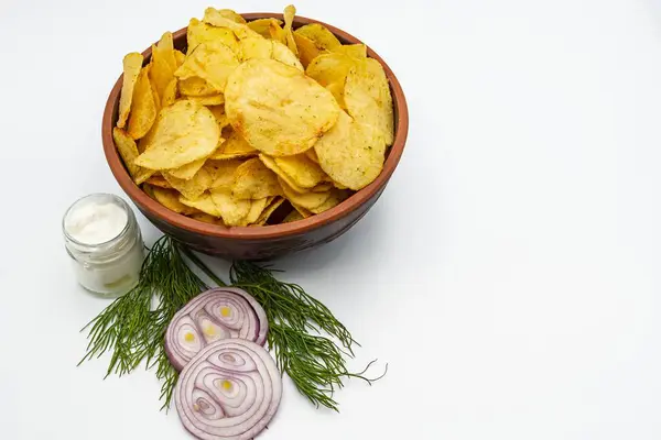 Beyaz arka planda soğanlı patates cipsi, sarımsak ve otlar..