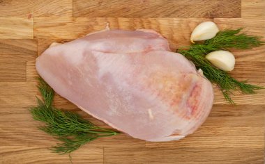 Tahta üzerinde taze çiğ tavuk göğsü, dereotu ve sarımsaklı..