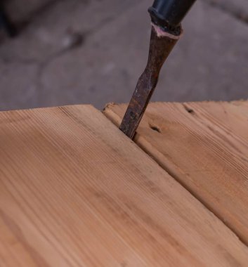 Bir marangozun ahşap tahtalarla çalışma süreci. Tahta panellerin arasına bir keski yerleştirildi.