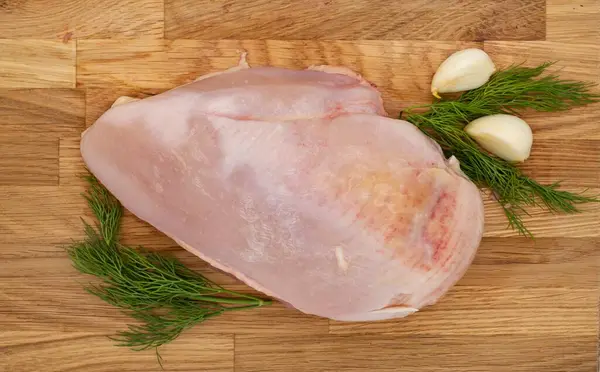 Tahta üzerinde taze çiğ tavuk göğsü, dereotu ve sarımsaklı..