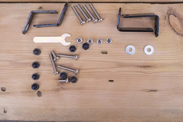 Ahşap bir yüzey üzerinde plastik bir sandalyeyi tamir etmek ve monte etmek için yedek parçalar. Farklı boyutlarda cıvatalar, fındıklar, anahtarlar..