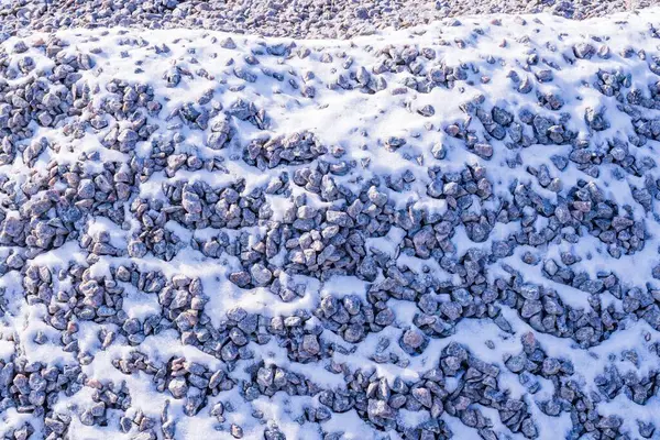 Karla kaplı moloz. Karda taş olan bir arka plan. İnşaat malzemeleri. Harabe dokusu.