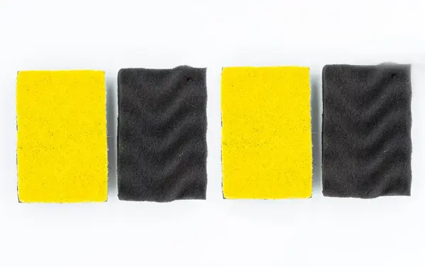 Beyaz arkaplanda bulaşık yıkamak için renkli süngerlerin yakın plan çekimi