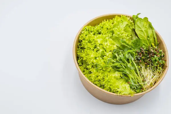 Beyaz arka planda bir kasede taze salata. Yakın plan taze organik yeşil salata ve kasede mikro yeşil salata. Sağlıklı yemek..