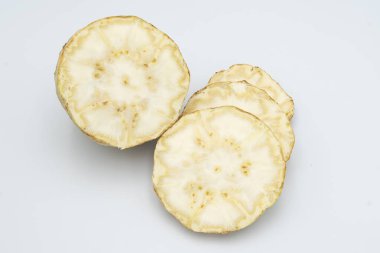 Beyaz zemin üzerinde taze dilimlenmiş kereviz kökü.