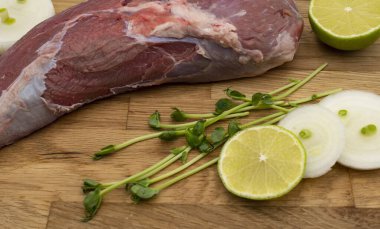 Tahta kesme tahtasının üzerinde soğan ve limonlu taze çiğ et..