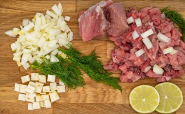 Fresh raw meat with dill, lime and vegetables on wooden background, close-up clipart