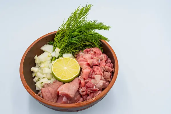 Beyaz arka planda ince doğranmış et, soğan, kereviz kökü, dereotu ve limon. Sırp çorba korbası malzemeleri.