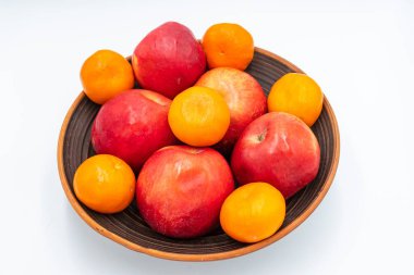 Olgun kırmızı elmalar ve turuncu mandalinalar beyaz arka planda bir tabakta. Meyveler, sağlıklı yiyecekler..