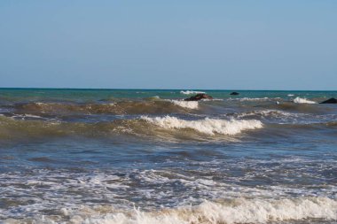 Denizde hafif bir fırtına. Beyaz köpüklü ve beyaz kapaklı dalgalar kumlu bir plajın kıyısında yuvarlanıyor. İspanya 'da tatil köyü. Deniz kıyısının güzel manzarası