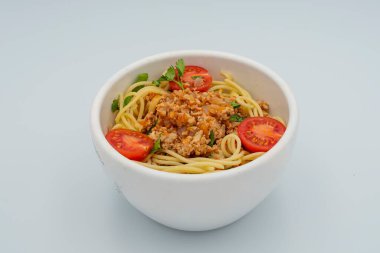 Et soslu makarna, kiraz domatesli ve beyaz arka planda maydanozlu makarna. İtalyan mutfağı.