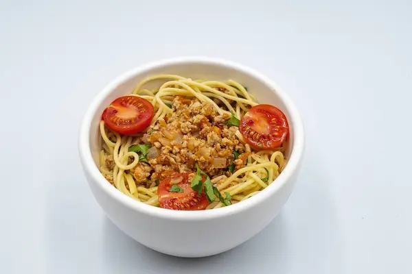 Et soslu makarna, kiraz domatesli ve beyaz arka planda maydanozlu makarna. İtalyan mutfağı.