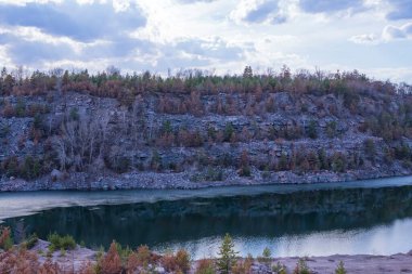 Göl ve ağaçlarla dolu güzel bir manzara. Granit kayalar ve çam ağaçları arasında bir taş ocağında. Terk edilmiş granit ocağı
