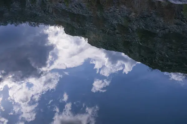 Bulutların ve etrafındaki doğanın yansıması granit ocağının suyunda, güzel su yüzeyinde, arka planda