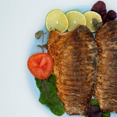 Domatesli ve limonlu kızarmış balık. Beyaz arka planda ızgara balık..