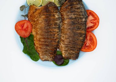 Domatesli ve limonlu kızarmış balık. Beyaz arka planda ızgara balık..