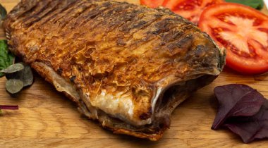 Ahşap bir tahtada kızarmış sazan balığı servis ettim. Domatesli, limonlu ve otlu kızarmış balık.