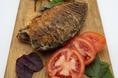 Ahşap bir tahtada kızarmış sazan balığı servis ettim. Domatesli, limonlu ve otlu kızarmış balık.