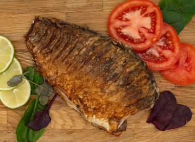 Ahşap bir tahtada kızarmış sazan balığı servis ettim. Domatesli, limonlu ve otlu kızarmış balık.