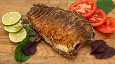 Ahşap bir tahtada kızarmış sazan balığı servis ettim. Domatesli, limonlu ve otlu kızarmış balık.