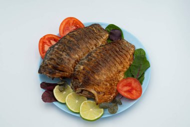 Domatesli ve limonlu kızarmış balık. Beyaz arka planda ızgara balık..