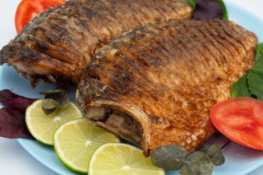 Domatesli ve limonlu kızarmış balık. Beyaz arka planda ızgara balık..