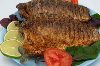 Domatesli ve limonlu kızarmış balık. Beyaz arka planda ızgara balık..