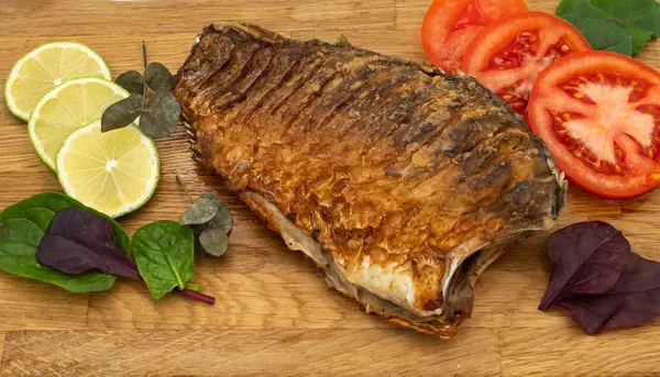 Ahşap bir tahtada kızarmış sazan balığı servis ettim. Domatesli, limonlu ve otlu kızarmış balık.