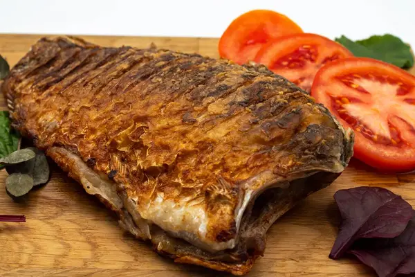 Ahşap bir tahtada kızarmış sazan balığı servis ettim. Domatesli, limonlu ve otlu kızarmış balık.