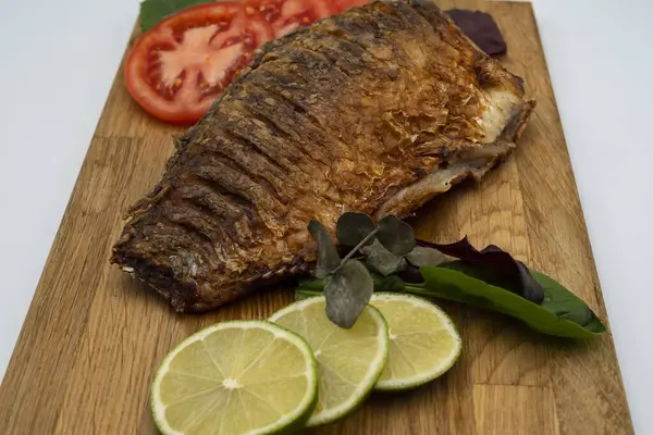 Ahşap bir tahtada kızarmış sazan balığı servis ettim. Domatesli, limonlu ve otlu kızarmış balık.