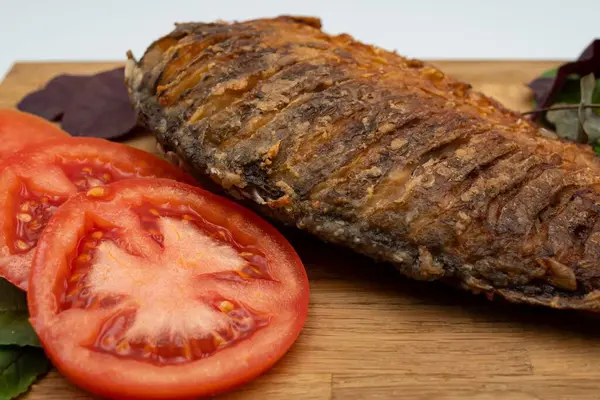 Ahşap bir tahtada kızarmış sazan balığı servis ettim. Domatesli, limonlu ve otlu kızarmış balık.