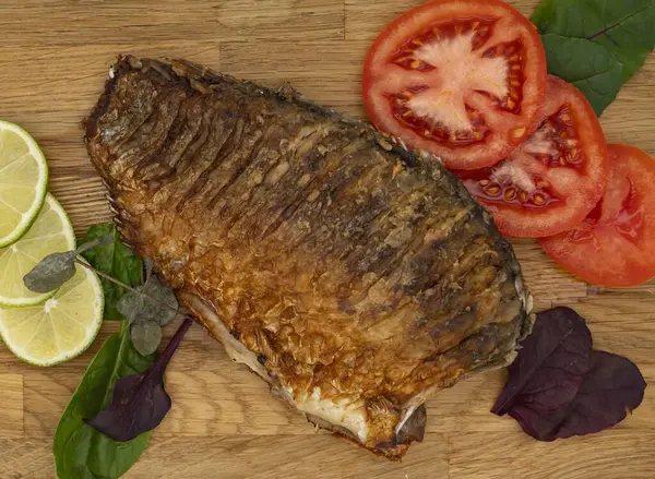 Ahşap bir tahtada kızarmış sazan balığı servis ettim. Domatesli, limonlu ve otlu kızarmış balık.