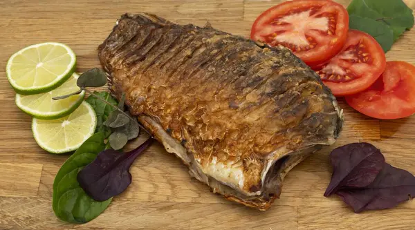 Ahşap bir tahtada kızarmış sazan balığı servis ettim. Domatesli, limonlu ve otlu kızarmış balık.