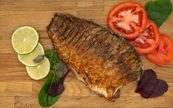 Ahşap bir tahtada kızarmış sazan balığı servis ettim. Domatesli, limonlu ve otlu kızarmış balık.