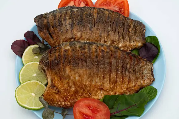 Domatesli ve limonlu kızarmış balık. Beyaz arka planda ızgara balık..